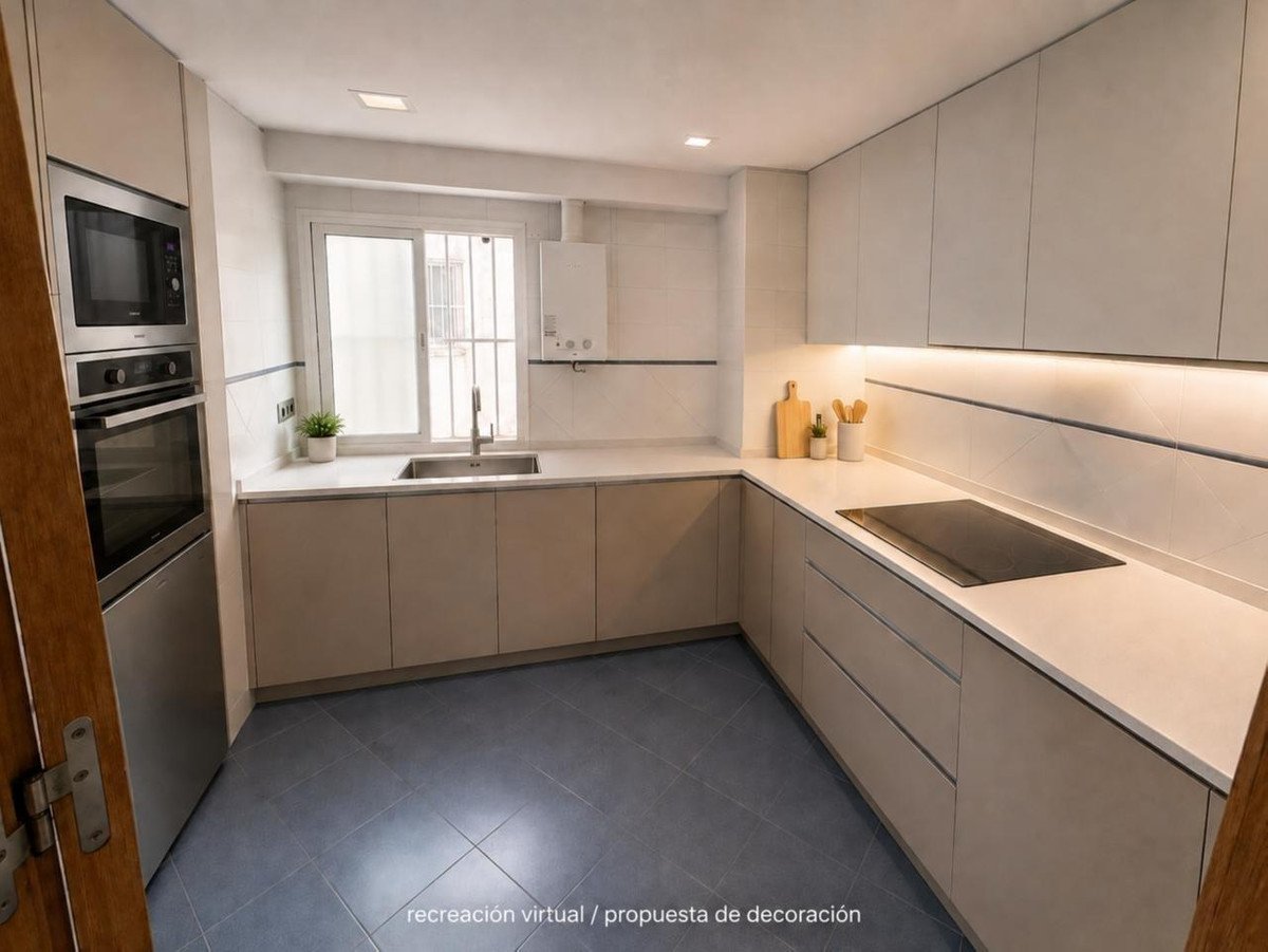 Modern kitchen with integrated oven and microwave, white countertops, induction hob, and light-colored cabinets.