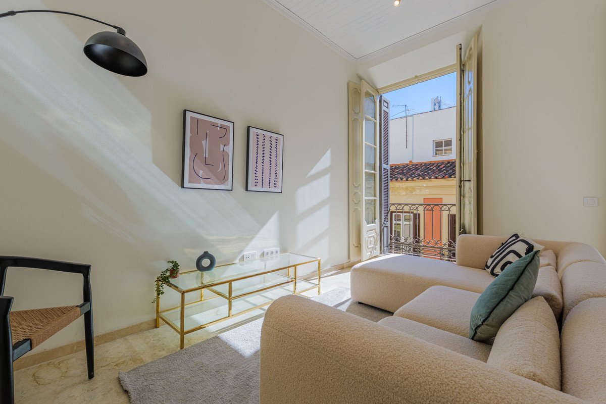 Cozy living room with a sectional sofa, modern coffee table, art, and a balcony with a city view.