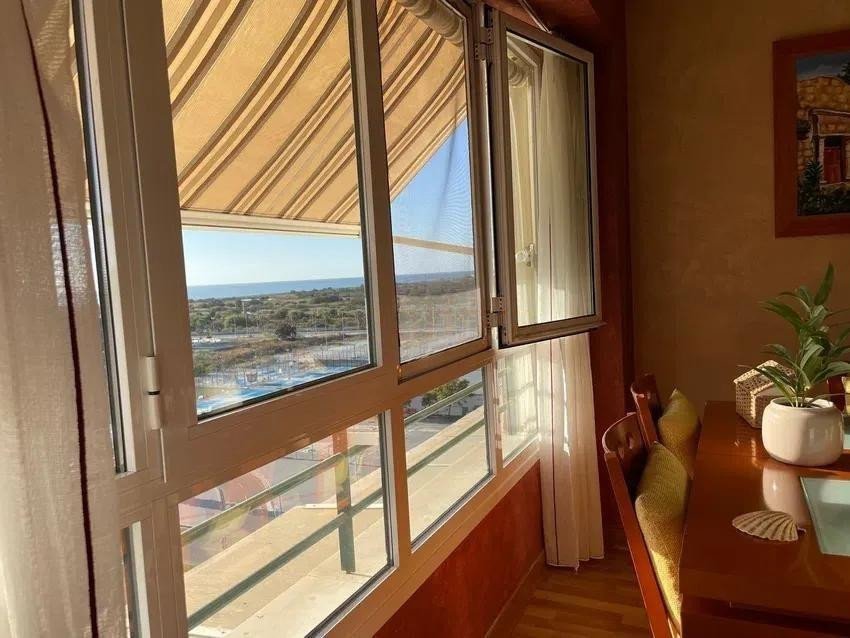 A dining area with a view of the sea through large windows with an awning.