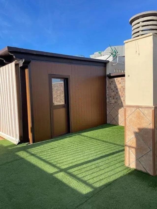 Exterior unit with artificial grass terrace and blue sky. Suitable for storage or as a small room.