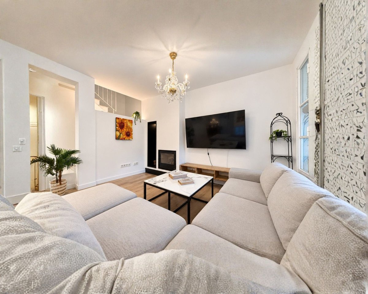 Modern living room with a large sectional sofa, a big TV, a fireplace, and a decorative chandelier.
