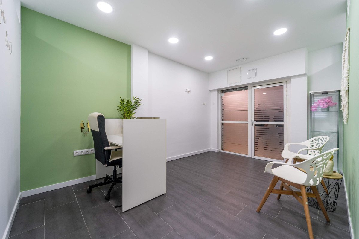 Modern office room with green accent wall, large window, and minimalist furniture.