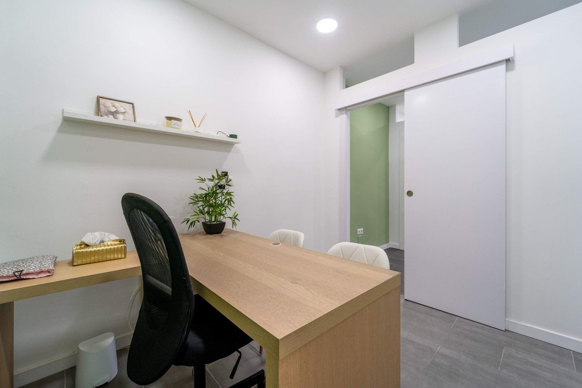 Minimalist home office with wooden desk, plant, and built-in shelf.
