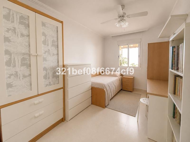A bedroom with a single bed, white wardrobe, chest of drawers, and a window with outdoor view.