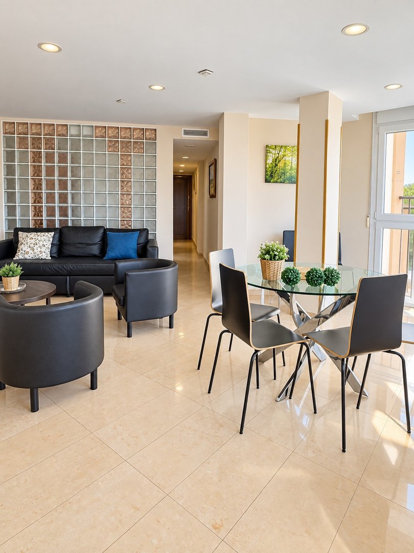Modern living and dining area with black leather sofa, glass dining table, and chairs. Decorated with glass block wall and artwork.