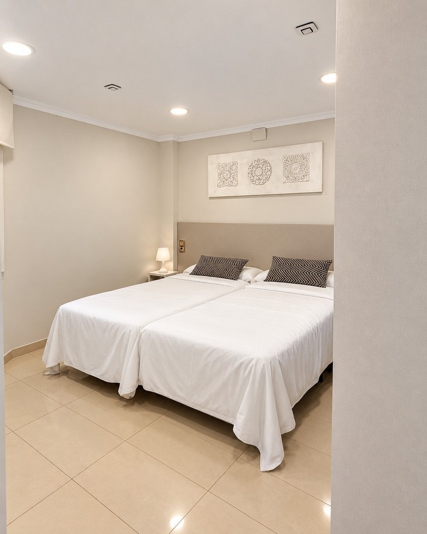 A clean bedroom with two twin beds, white linens, and modern geometric wall art above the headboard.