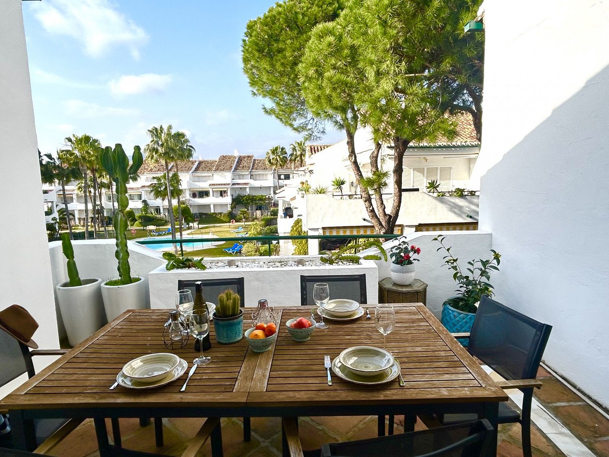 Terrace dining table set for meals with a view of the pool and surrounding buildings.