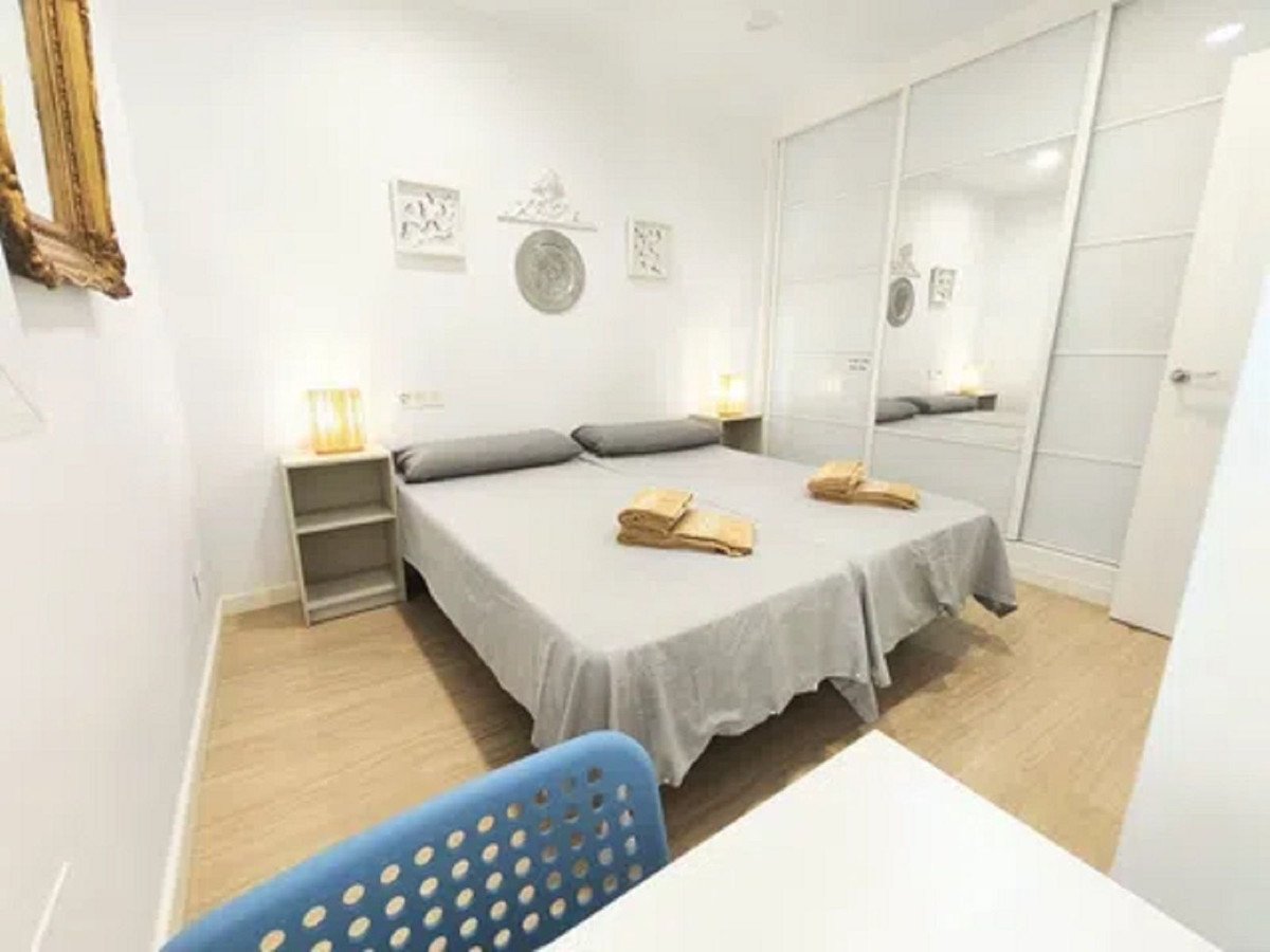 A bedroom with two beds, bedside tables with lamps, and a large mirrored closet with sliding doors.