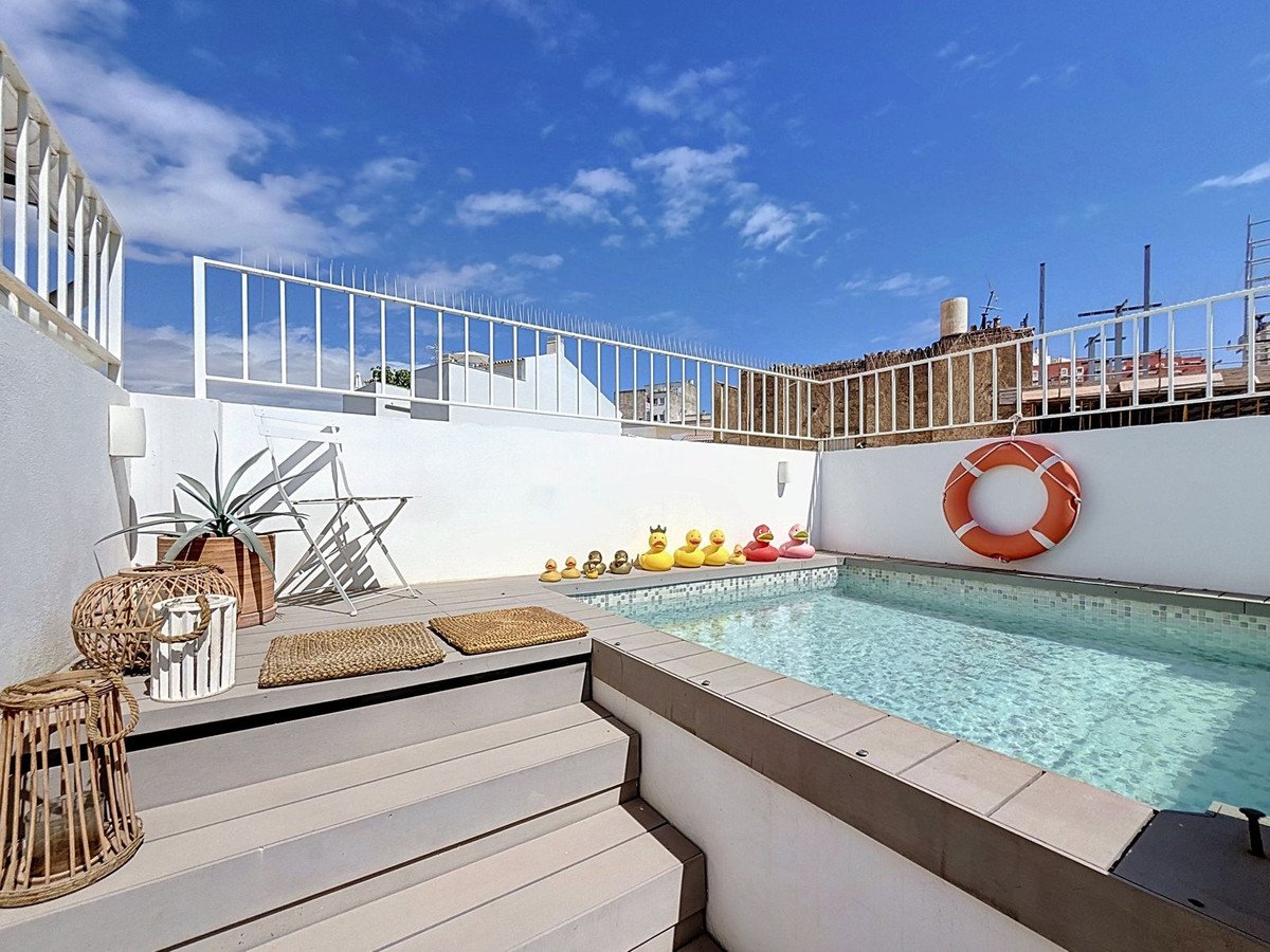 A rooftop terrace with a small swimming pool, outdoor seating area, and a lifebuoy on the wall.