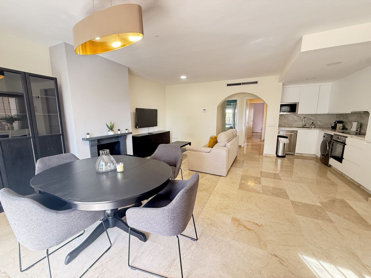 Spacious open-plan living, dining, and kitchen area with modern furniture, marble flooring, and a fireplace.