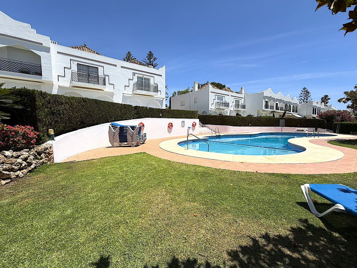 Villa with pool, lawn, and white buildings under blue sky.