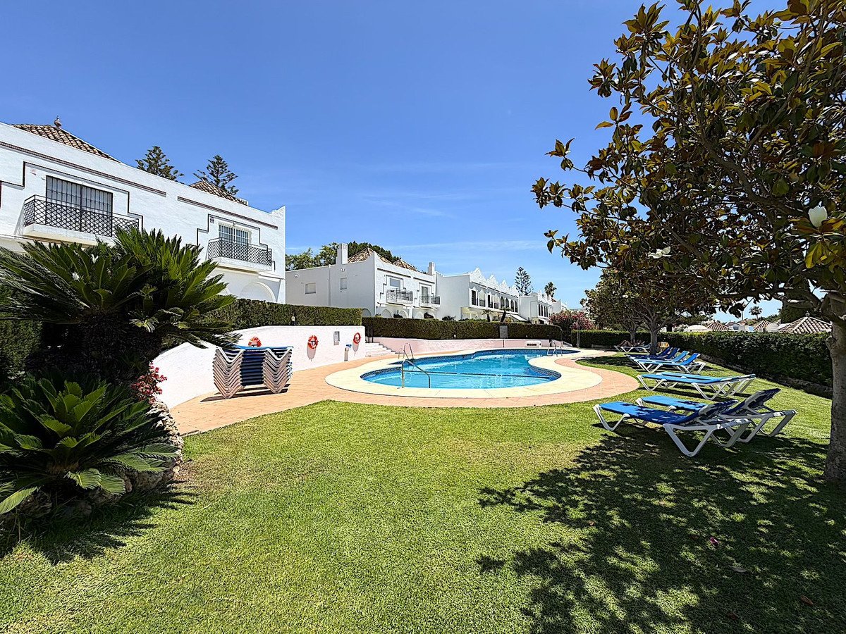 Villa with pool, lounge chairs, and green lawn under clear blue sky.