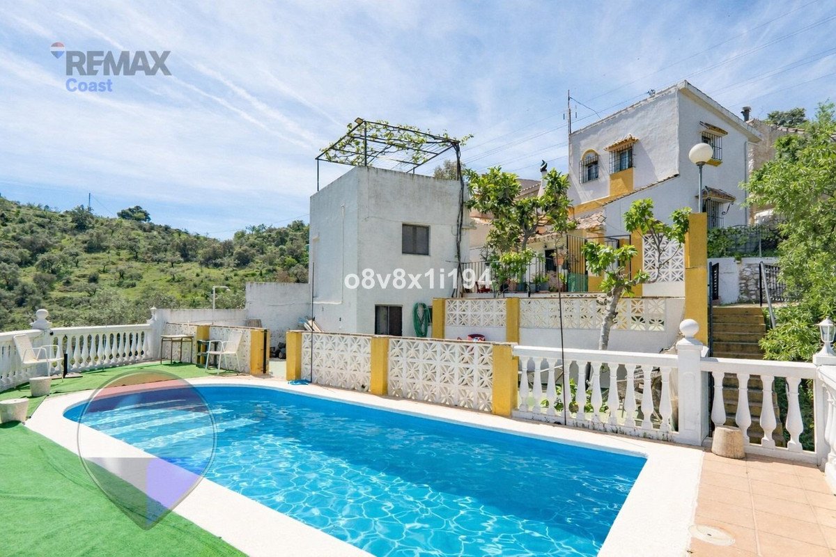 Villa with swimming pool and terrace overlooking a lush green hillside under a clear blue sky.