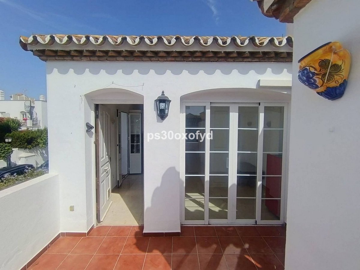 A sunny terrace with terracotta tiles, featuring sliding glass doors and a traditional tiled roof.