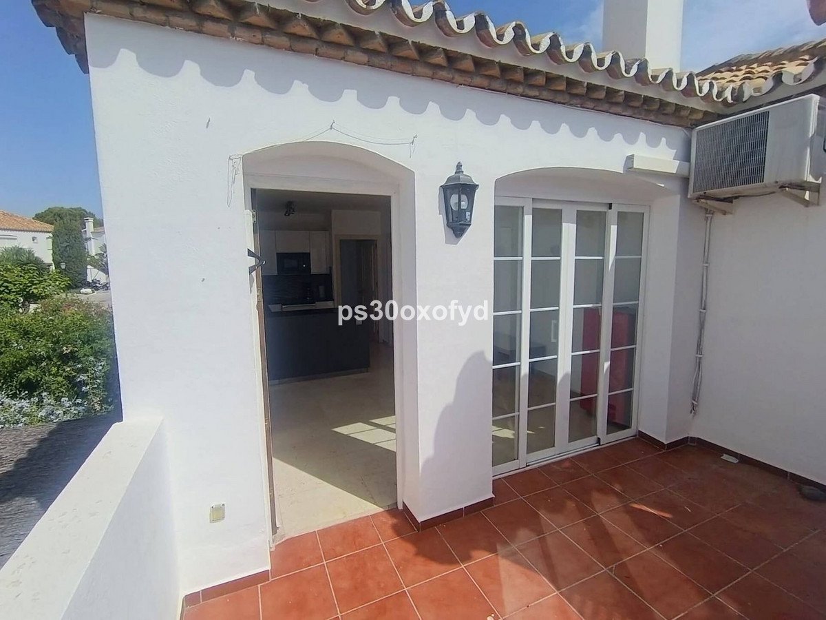 Terrace view of an open kitchen and sliding glass doors on a sunny day.