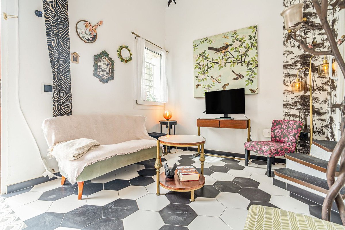 A stylish living room with a sofa, armchair, coffee table, and TV against a wall with unique hexagonal floor tiles.