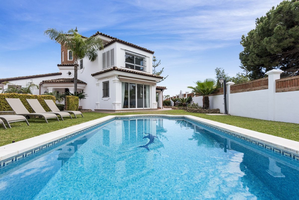 Luxurious swimming pool with a white house and lounge chairs