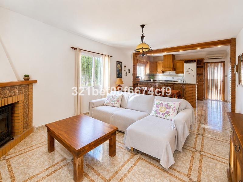 Cozy living room with a fireplace, a sofa, a coffee table, and an open-plan kitchenette visible in the background.