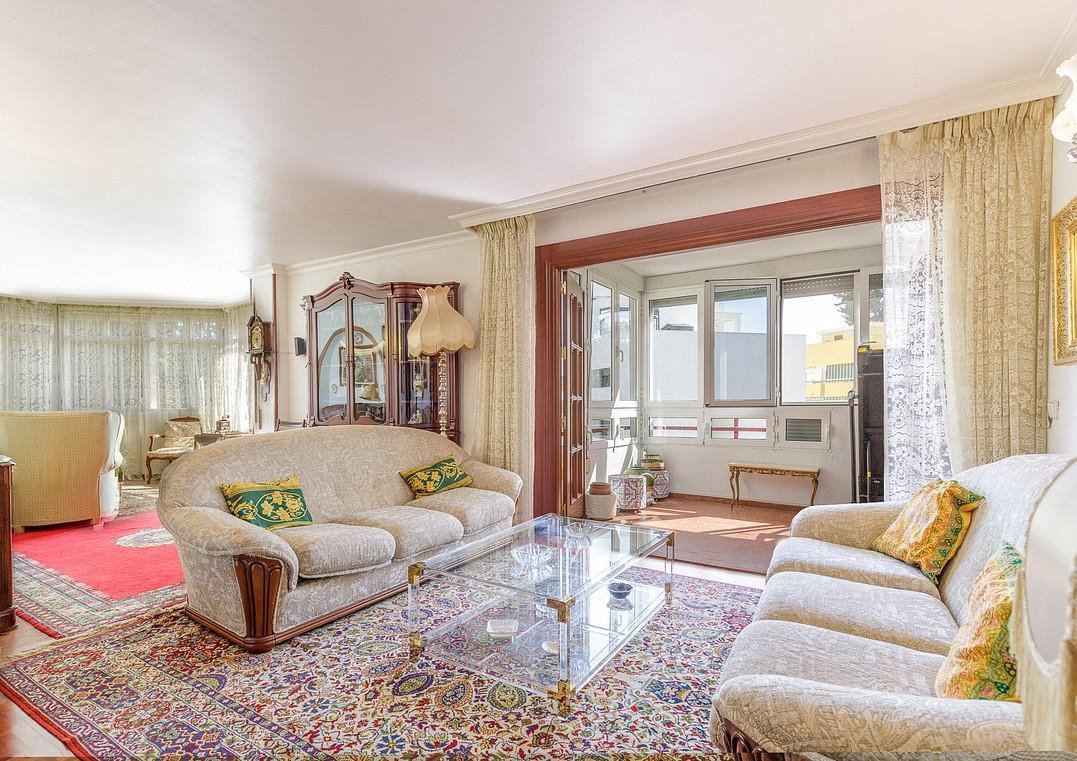 Spacious living room with sofas, glass coffee table, and balcony view