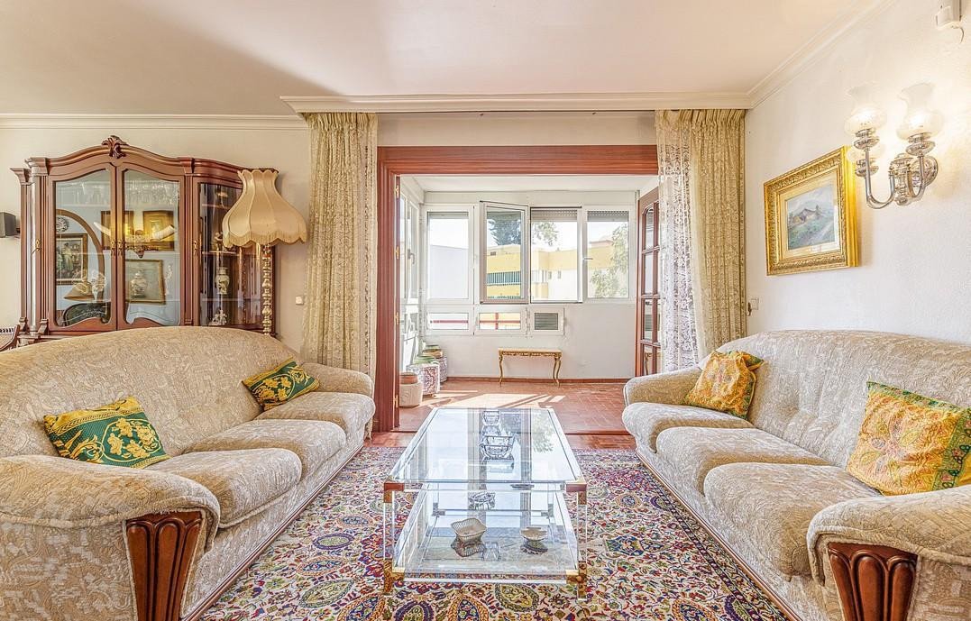 A cozy living room with two sofas, a glass coffee table, and a view to an outdoor patio.