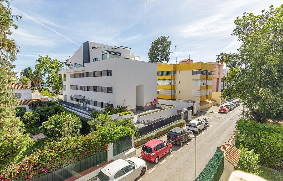 Modern apartment building with street view, parked cars, and greenery