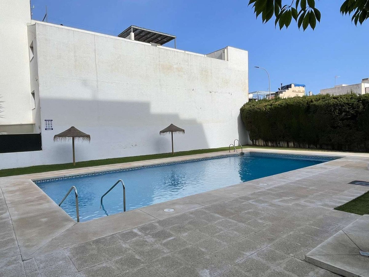 Swimming pool with two sun loungers and umbrellas against a white wall