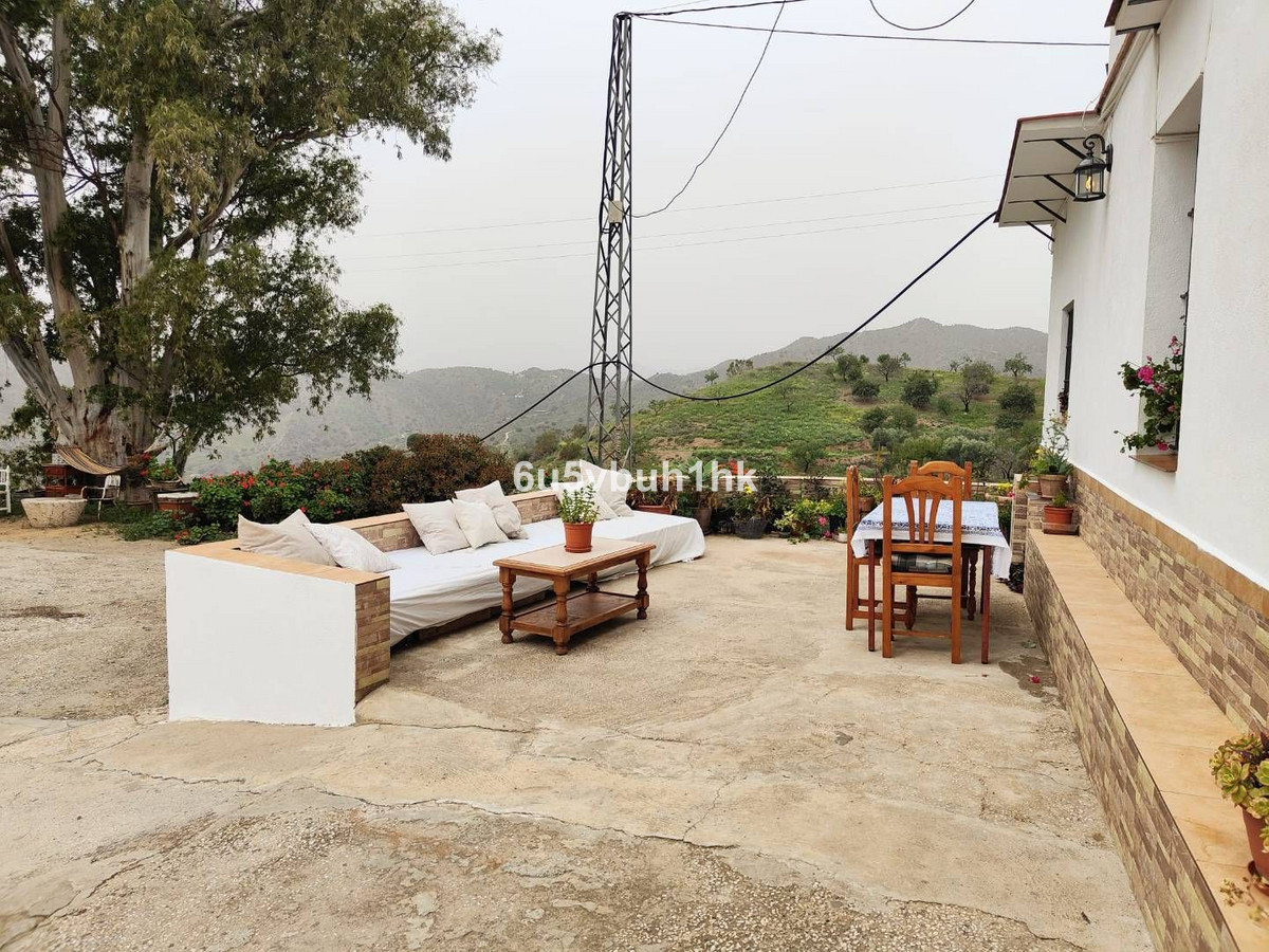 Outdoor patio with mountain view, sofa, dining table, and potted plants.