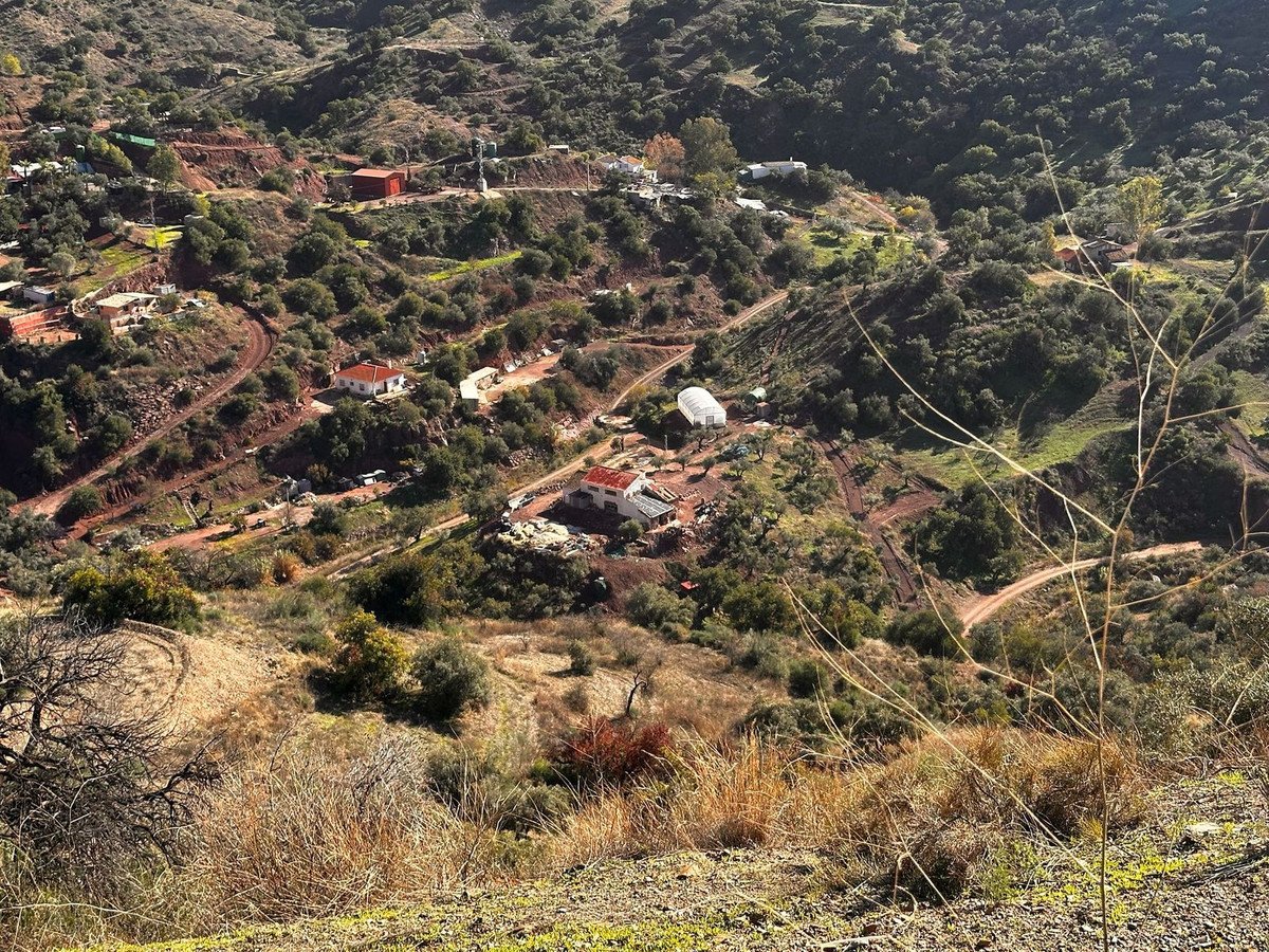 Rustic mountain home with panoramic views, surrounded by lush greenery and winding paths.