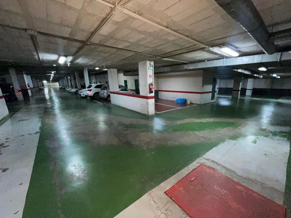 Ondergrondse parkeergarage met geparkeerde auto's en groene vloer.