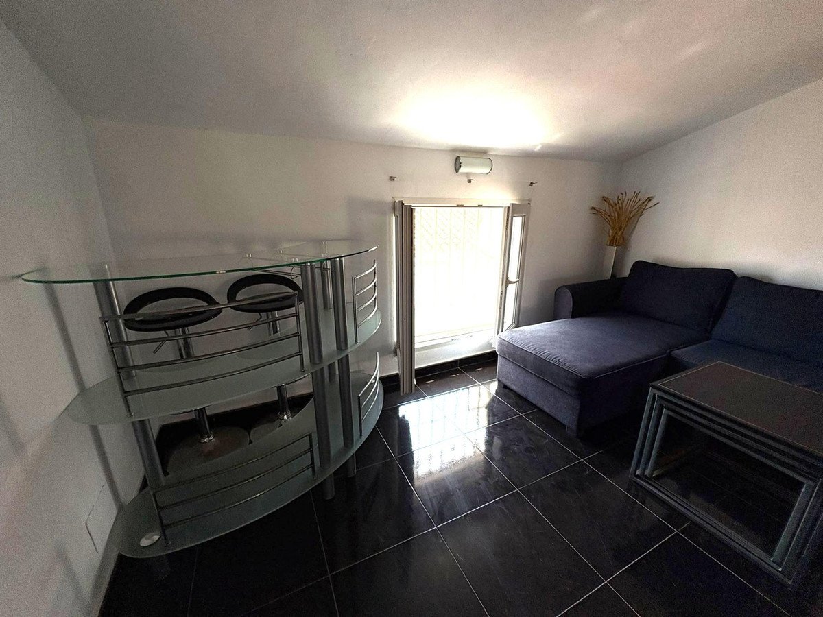 Modern living room with black tiled floor, blue sofa, glass bar unit, and large window.