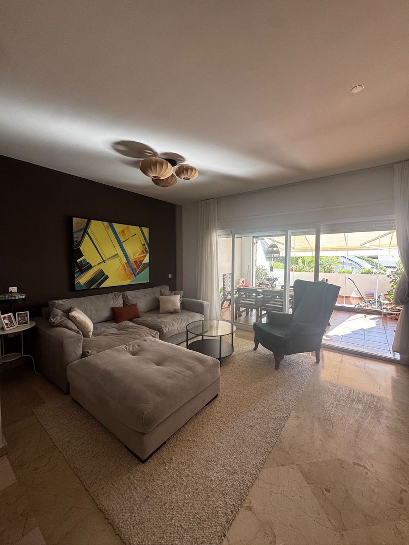 Spacious living room with a large sectional sofa, armchair, coffee table, and access to a terrace with outdoor seating.