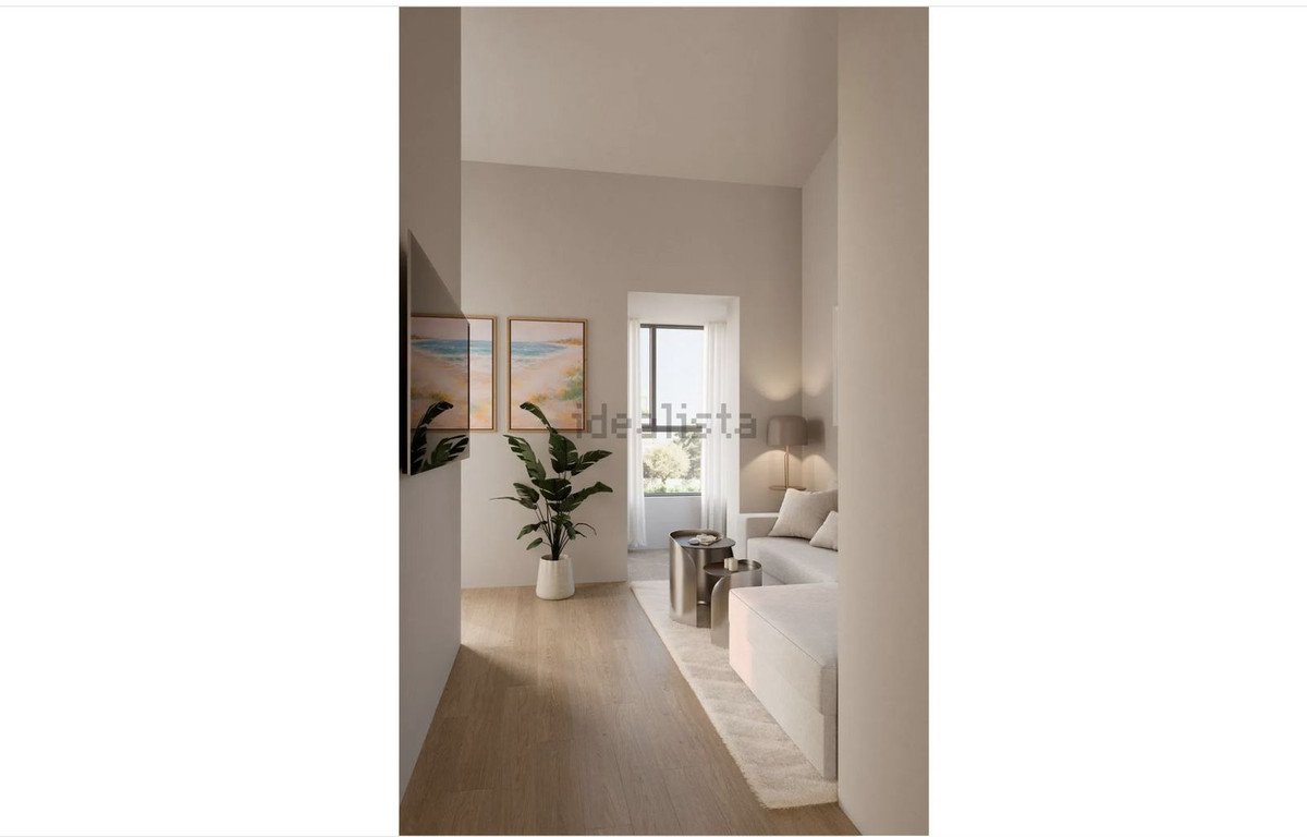 Modern living room with large windows, light-colored furniture, and a potted plant.