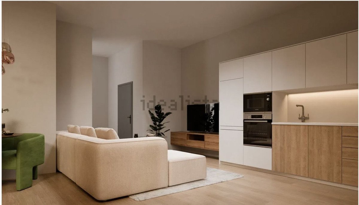 Modern living room with kitchenette, beige sofa, and wooden flooring.