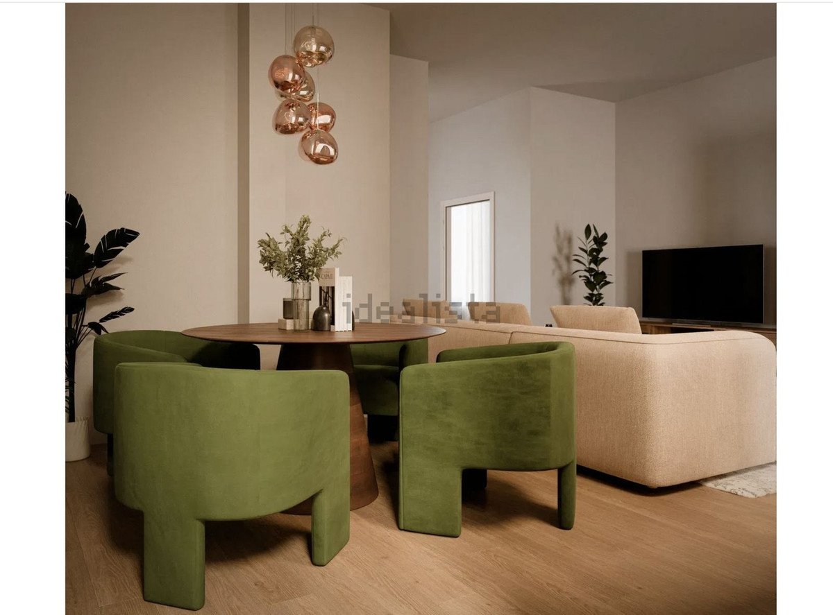 Modern living room with green chairs, wooden floor, and a large TV.