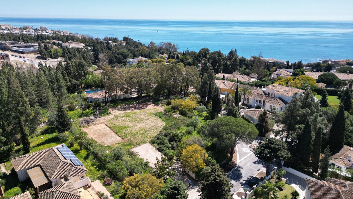 Aerial view of a Mediterranean estate with lush greenery, a swimming pool, and distant sea views.
