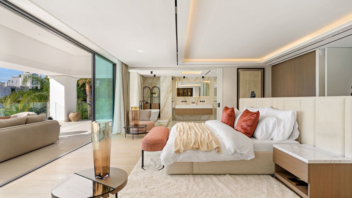 Luxurious master bedroom with king-size bed, open-plan bathroom, and direct access to an outdoor terrace with sea views.