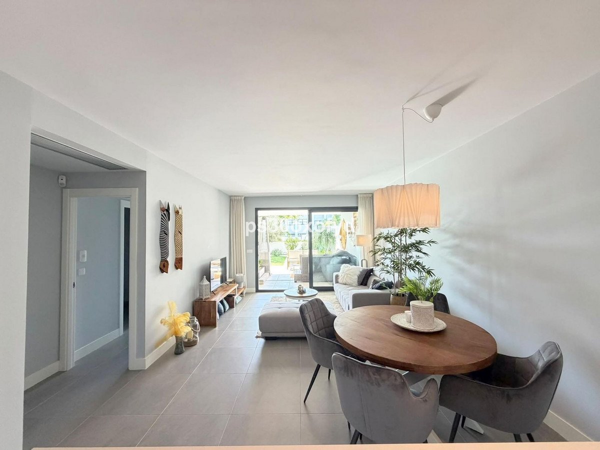 Modern dining and living area with plush seating, a round wooden table, and sliding doors leading to a terrace.