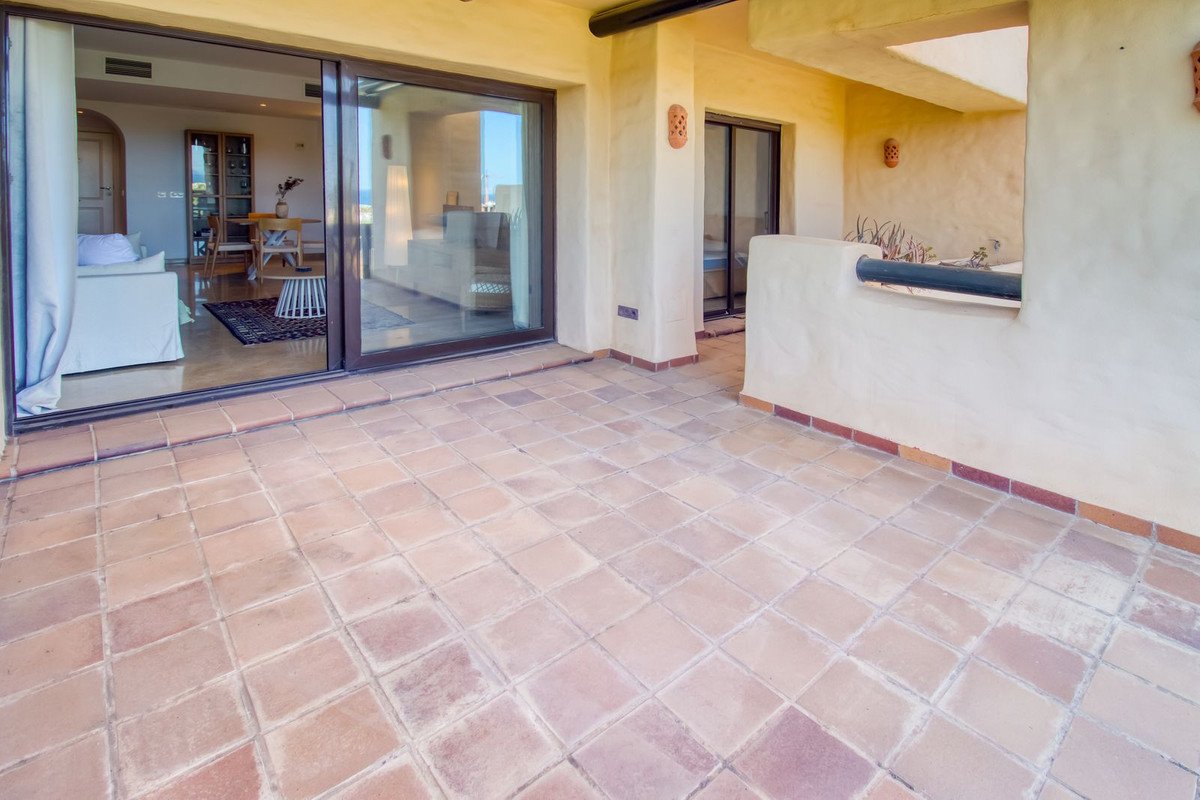 Terracotta tiled terrace with glass sliding doors leading to a living room with sea views.