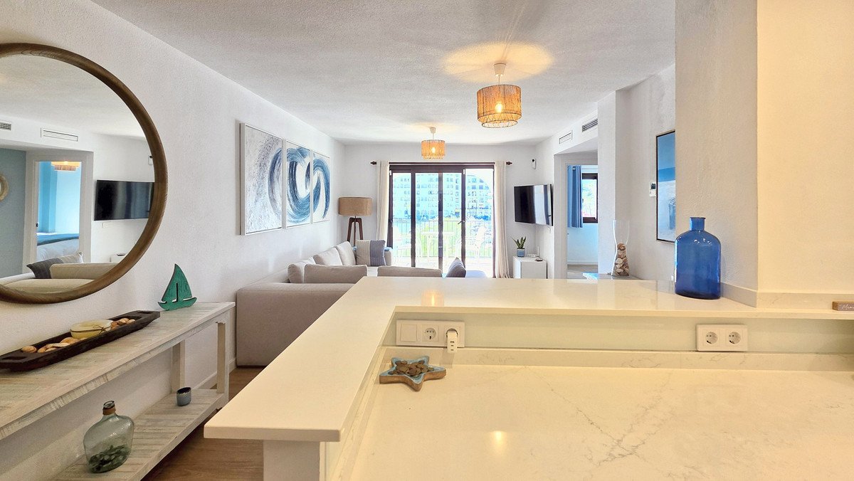 Open-plan living room with ocean view, modern decor, and large windows