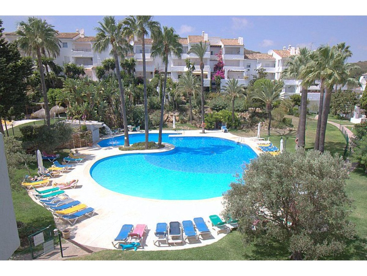 A beautiful resort swimming pool with palm trees, lounge chairs, and apartment buildings in the background.