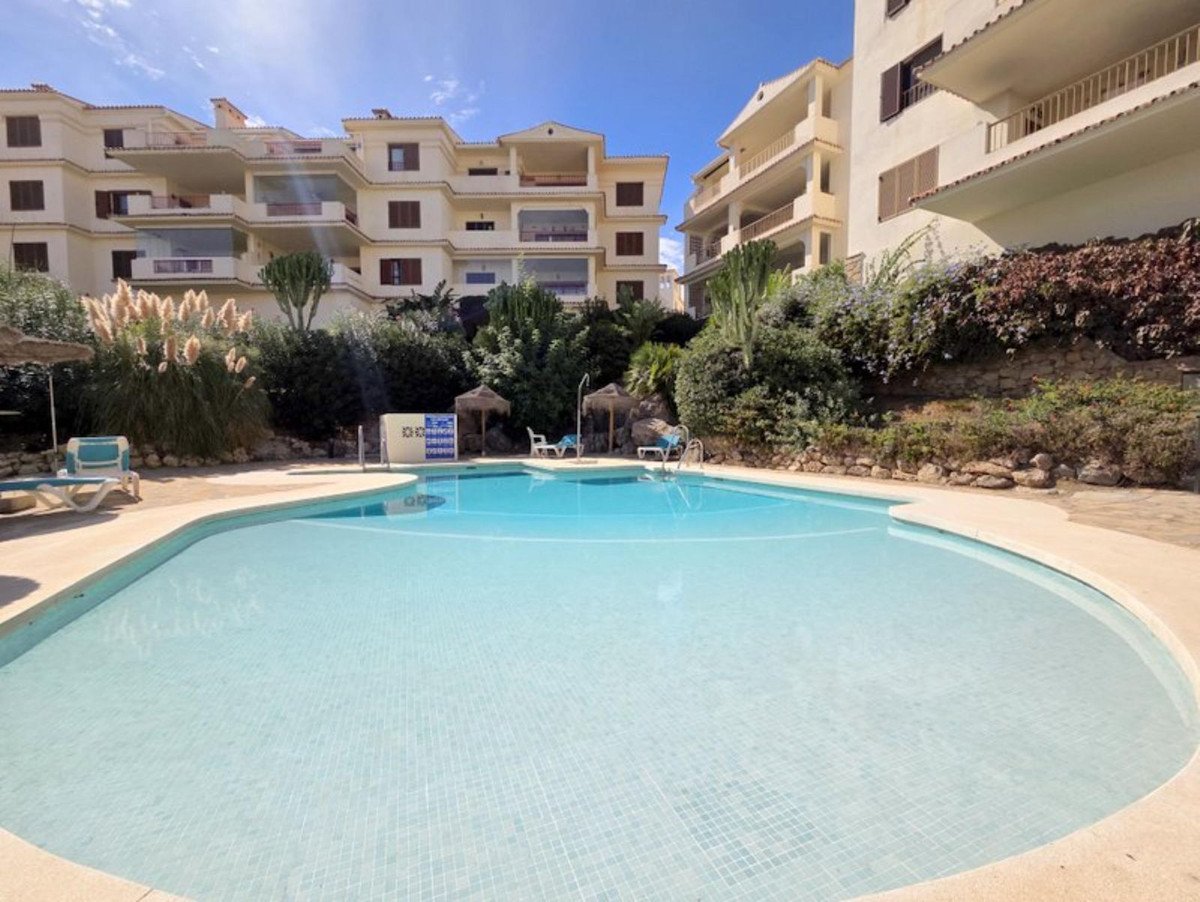 Exterior view of a swimming pool area with apartment buildings in the background on a sunny day.