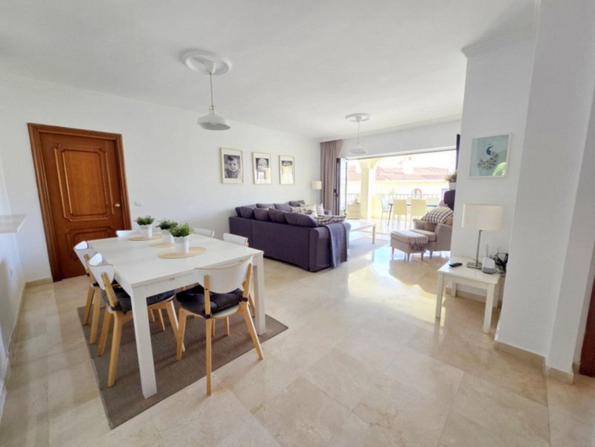 Spacious living and dining area with a terrace view, featuring a dining table, sofa, and comfortable armchair.