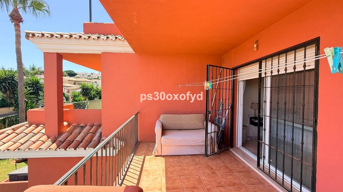Terrace with a sofa, clothesline, and view of palm trees and houses under a sunny sky.