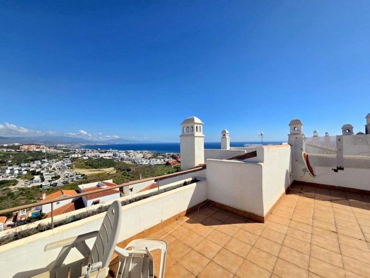 Terrace with sea view and white chimneys, overlooking a coastal town on a sunny day.