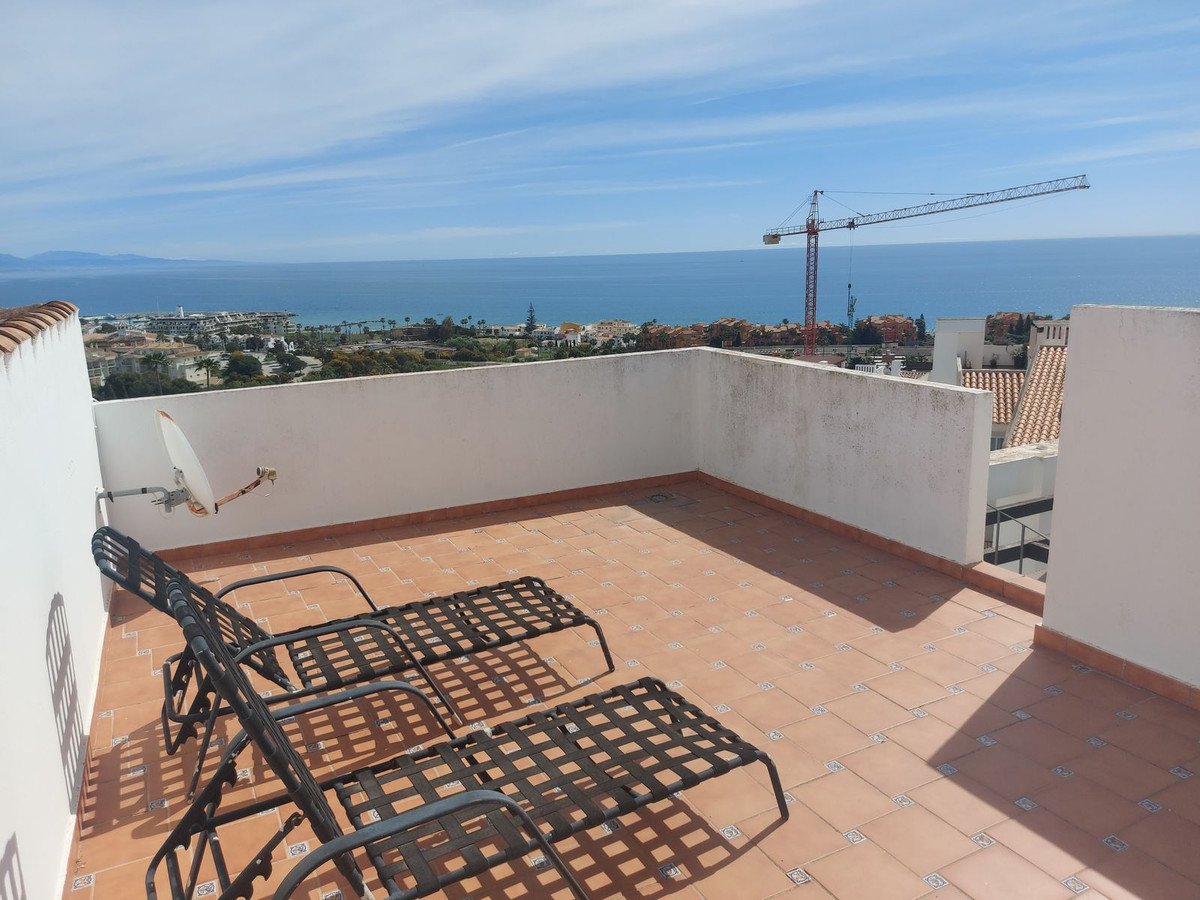 Terrace with two lounge chairs overlooking the sea and a distant coastline.