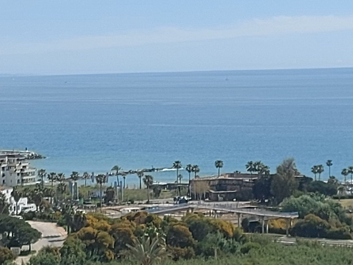 A picturesque view of the sea from a resort with palm trees and buildings visible below.