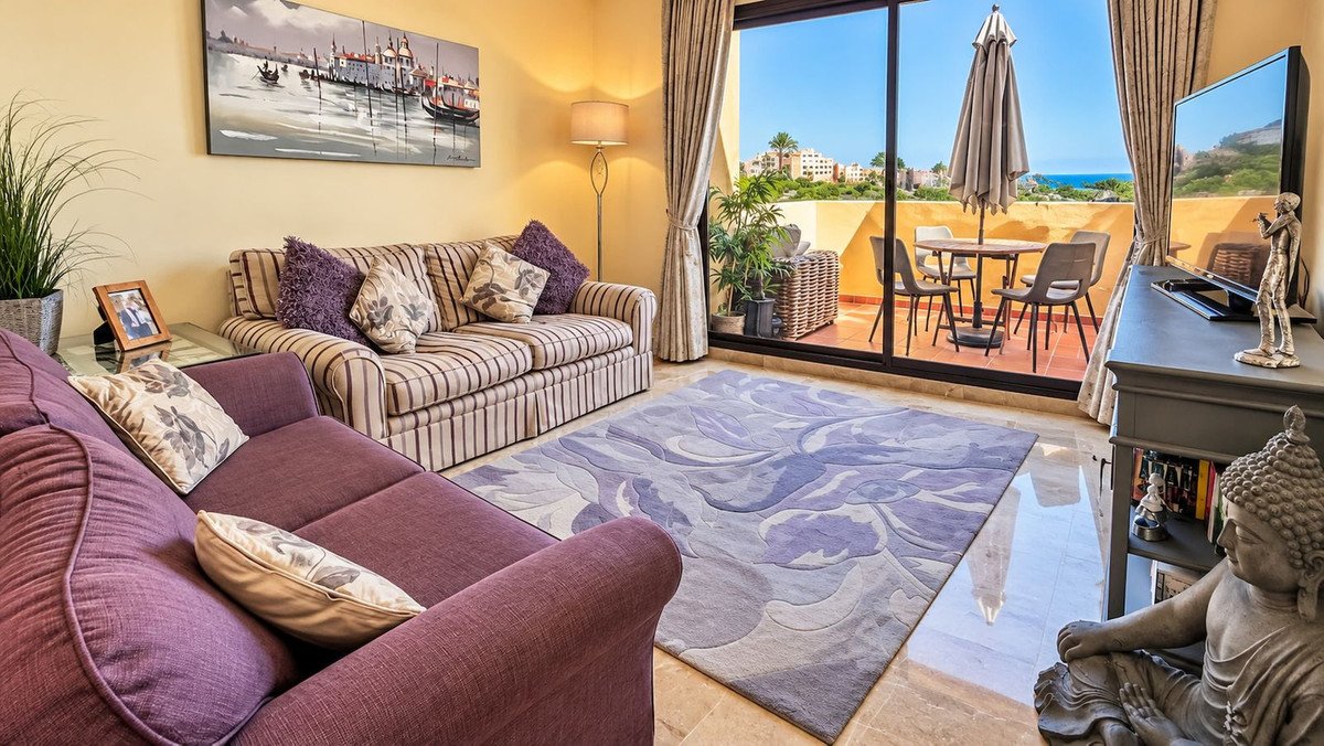 Living room with striped sofa, purple armchair, and ocean view patio
