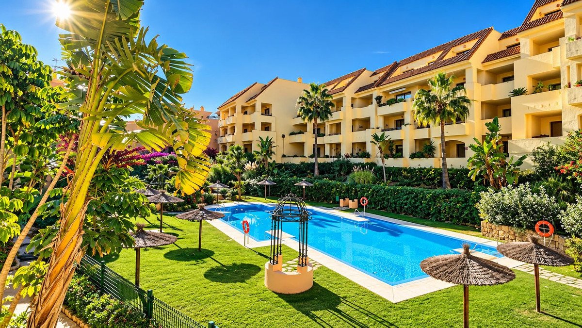 Apartment complex with swimming pool, sunlit garden, and palm trees