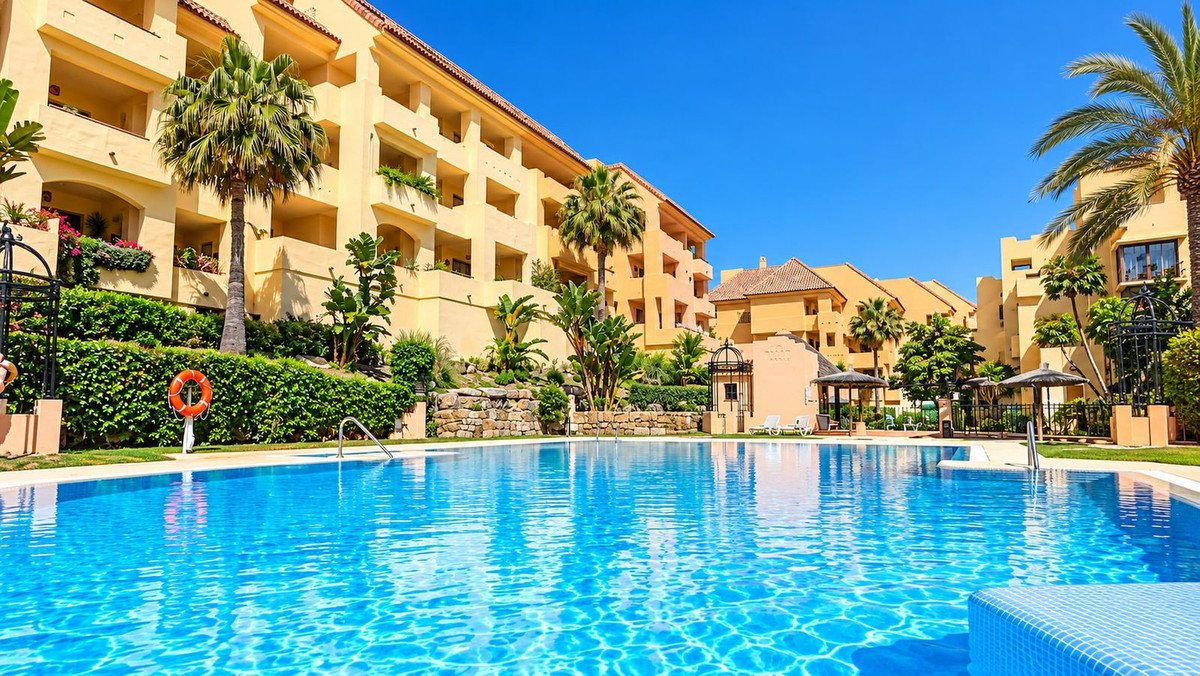 Swimming pool at an apartment complex with palm trees and yellow buildings