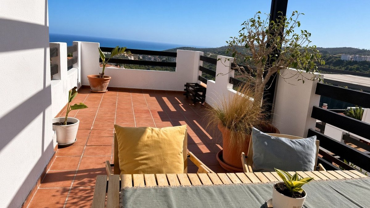 Terrace with tiled floor, seating, potted plants, and a beautiful sea view under a clear blue sky.